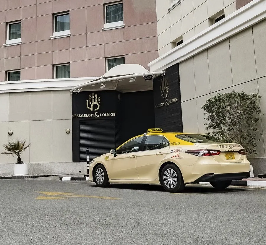 Dubai taxi on highway with city skyline in backgr…